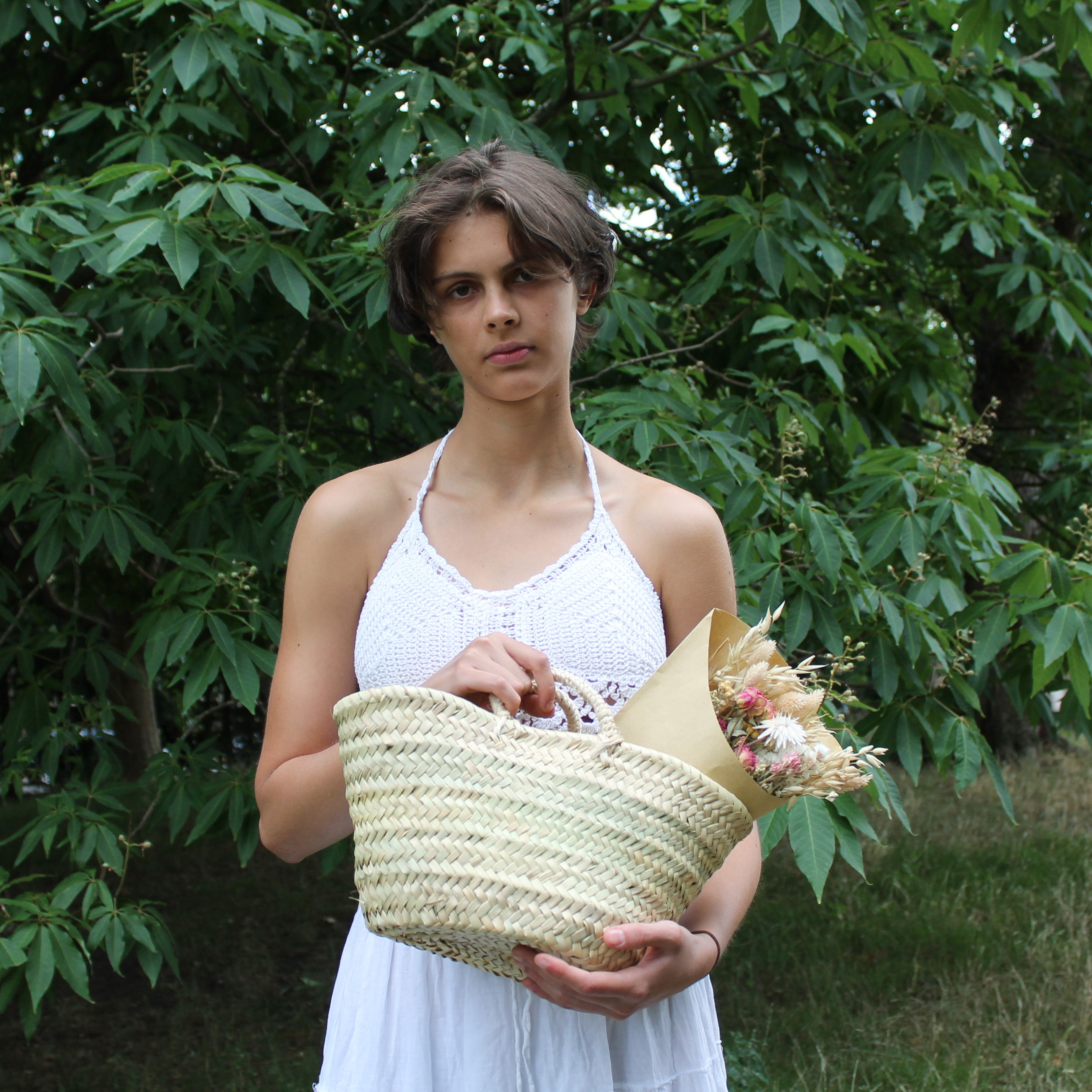 Woman holding a woven basket with flowers in a natural setting