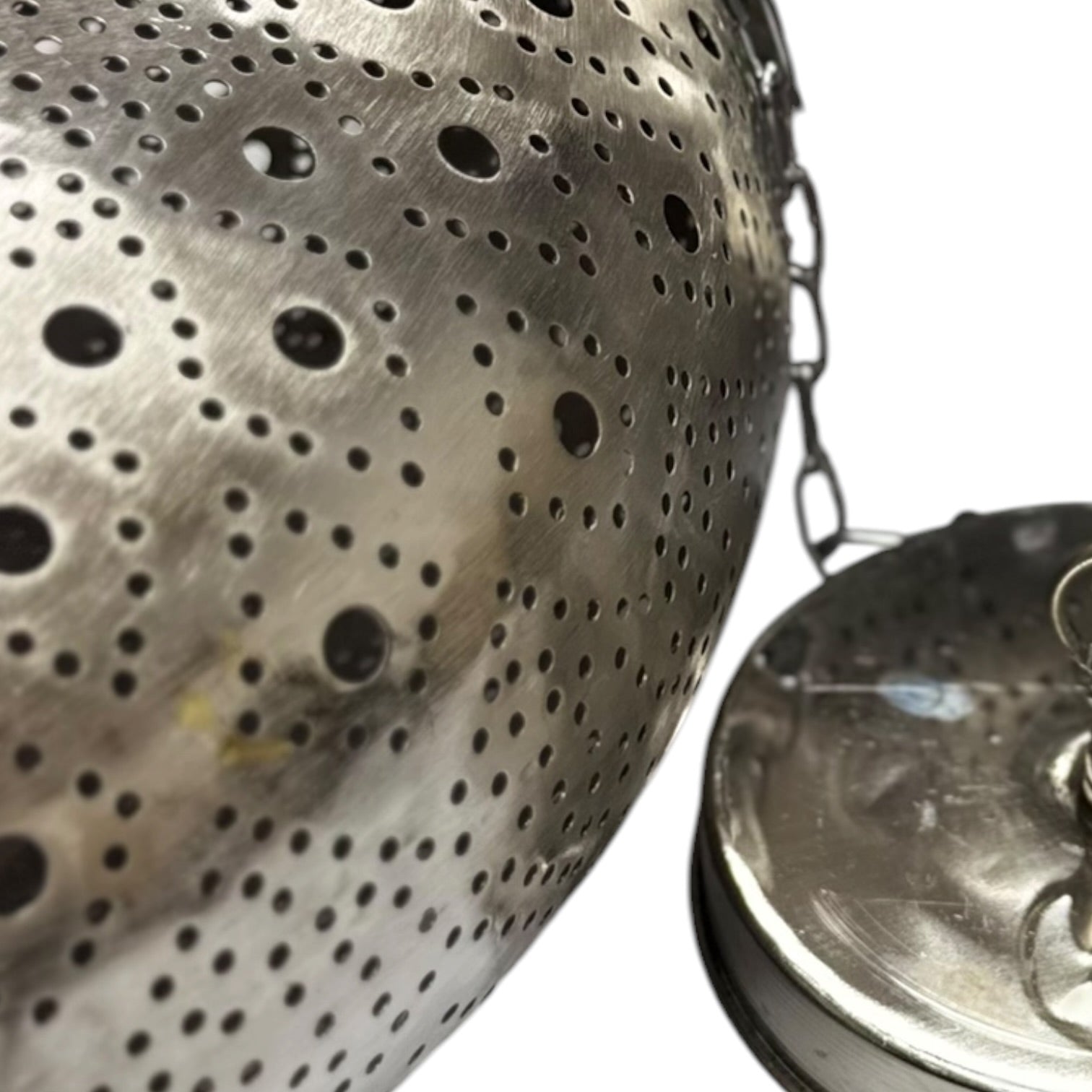 Metallic tea infuser with perforated design on a white background