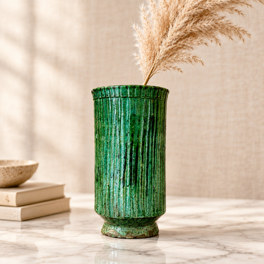 Tall emerald green Tamegroute ceramic fluted cylinder vase on wooden display shelf
