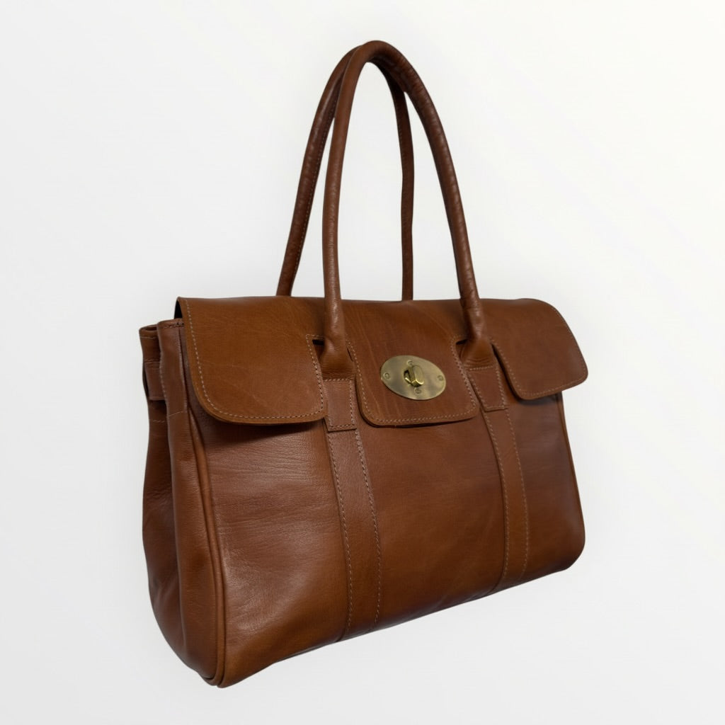 Brown leather handbag with a gold clasp on a white background