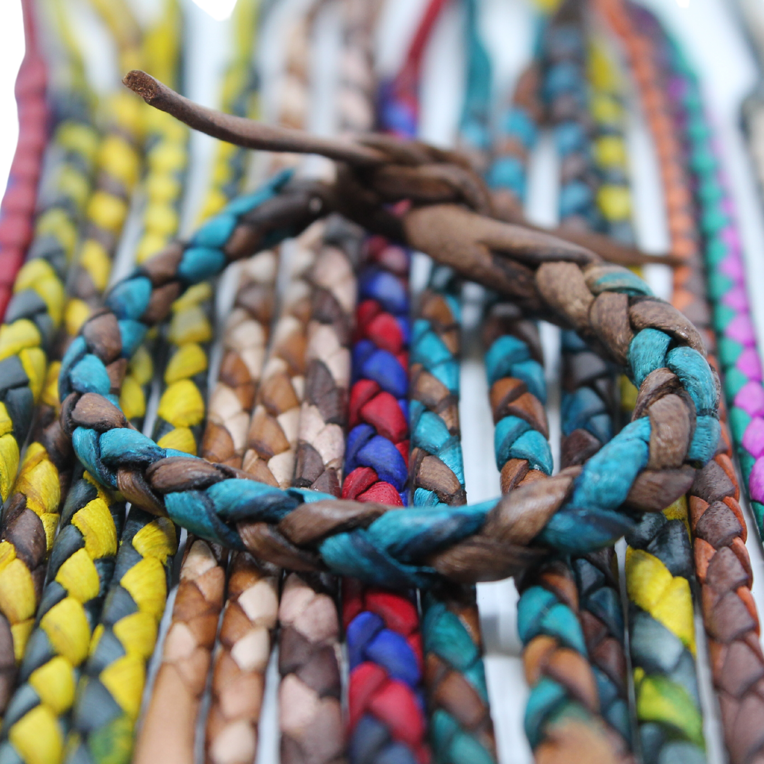 Adjustable twisted artisan leather bracelet jewelry for men and women displayed with colorful braided bracelets